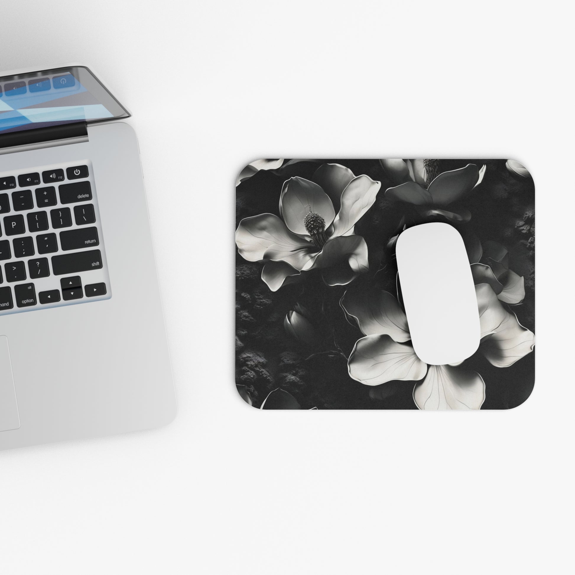 Monochrome Magnolia mouse pad beside laptop displaying black and white floral artwork