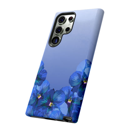 Blue pansy floral gradient Samsung Galaxy phone case shown in angled view with soft blue aesthetic background