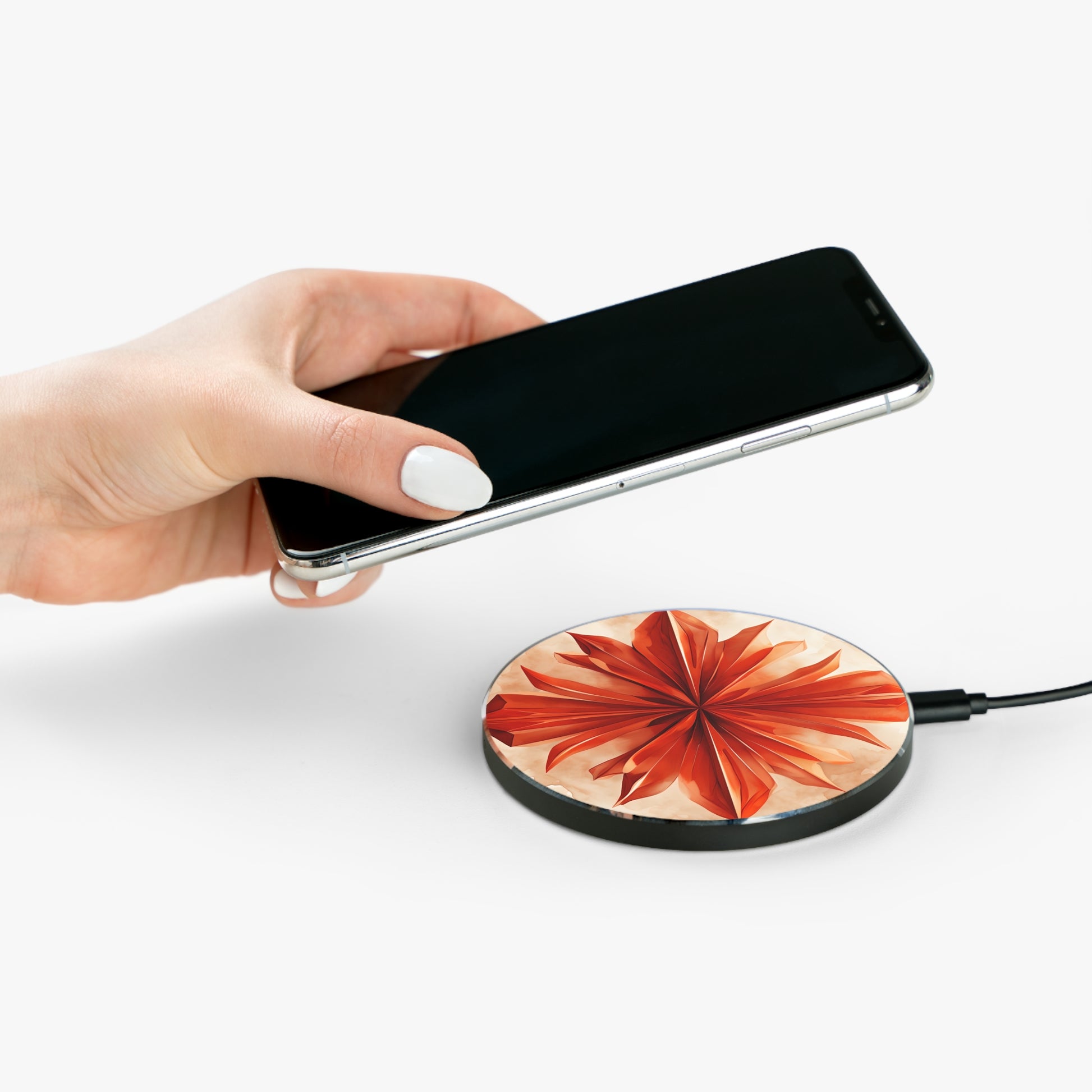 Hand placing smartphone on Sunset Fleur orange floral mandala design Qi wireless charger