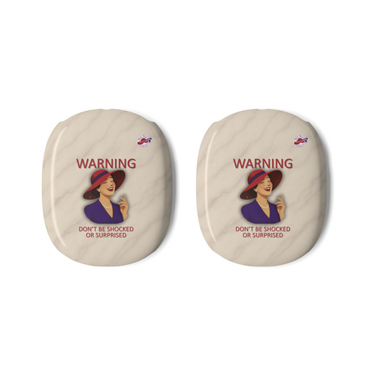 Two oval-shaped beige AirPods Max covers with a vintage warning label featuring a laughing woman in a red hat and the text 'WARNING DON'T BE SHOCKED OR SURPRISED', alongside the Red Hat Society Logo shown on a plain white background.